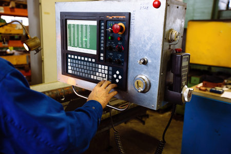 Factory engineer adjusting operation parameters of CNC lathe machine.