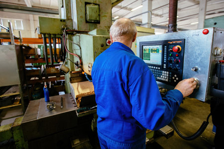 Factory engineer adjusting operation parameters of CNC lathe machine.