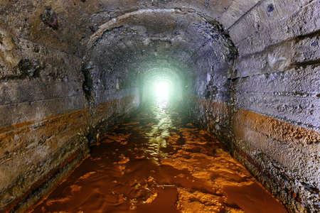 Dark dirty flooded concrete vaulted drainage mine tunnel.の写真素材