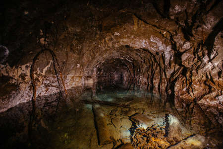 Dark flooded abandoned mine tunnel with water reflections.の写真素材