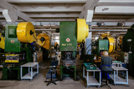 Worker operates metal press stamping machine. Production of press forms for cookies.