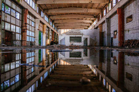 Inside of flooded dirty abandoned ruined industrial building with water reflection.の写真素材