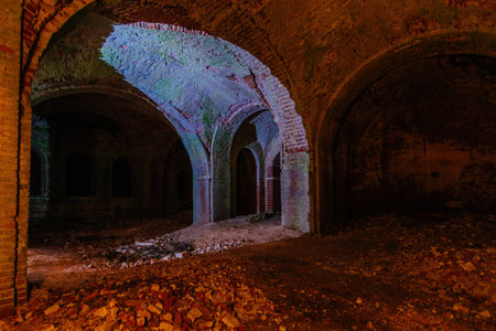 Dark corridor of old ancient abandoned red brick ruined historical building.