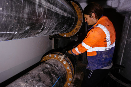 Worker installing water pipeline system in technical tunnel