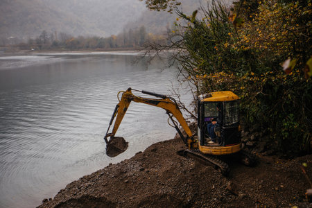 Light excavator at earthmoving works on the lakeの写真素材