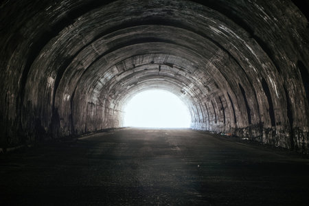 Old underground road tunnel inside mountain. Light at the end of the tunnel.