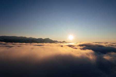 Caucasian mountains above the clouds at the sunset. Cloudscape, aerial view.