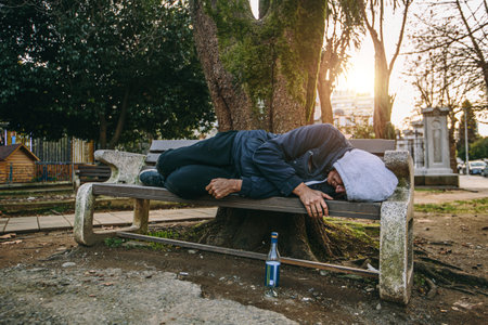 Homeless man or alcoholic sleeping on bench. Poor man on city street.の写真素材