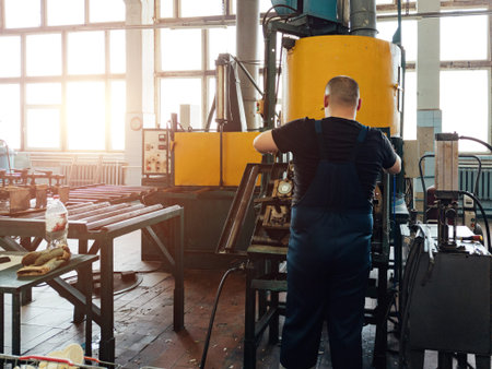 Worker operates plastic stamping forming machine in workshop.