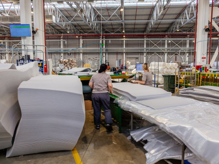 Workers at foam rubber cutting machine.