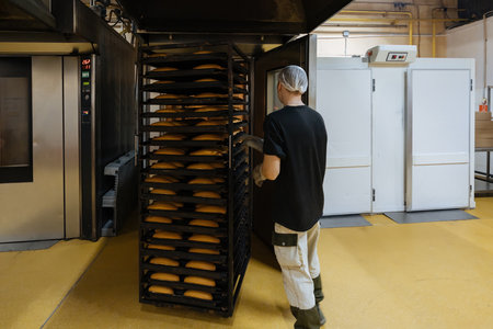 Confectionery manufacturing. Baker puts loafs into oven for baking.の写真素材