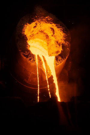 Metal casting process in metallurgical plant, molten metal is pouring from ladle, close up