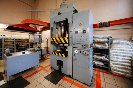 Hydraulic press for rubber and plastic casting in workshop.