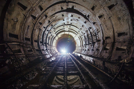 Dark dirty abandoned subway tunnel with rusty railway.