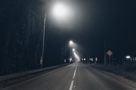 Foggy misty night road illuminated by street lightsの写真素材