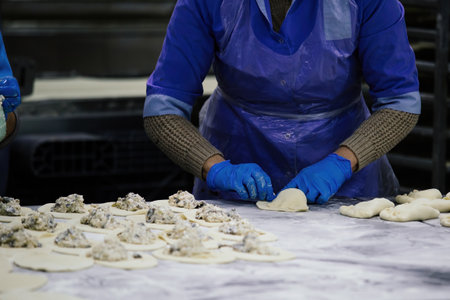 Baker kneading dough and making pies at bakeryの写真素材