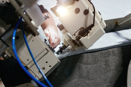 Worker sewing edges of mattress with sewing machine.の写真素材