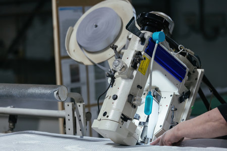 Worker sewing edges of mattress with sewing machine.の写真素材