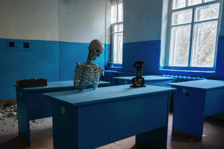Skeleton seating at desk of abandoned school.の写真素材
