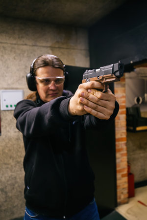 Person aiming gun in shooting range, selective focus.