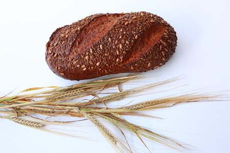 A loaf of pure rye bread and rye ears on a white backgroundの写真素材
