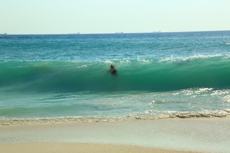 Big wave in the Caribbean sea is breaking the coast and swallowing a female. Great nature background.の写真素材