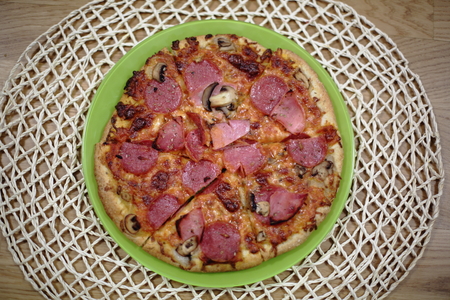 Pizza sliced ??on green plate. Closeup view. Food background.の写真素材