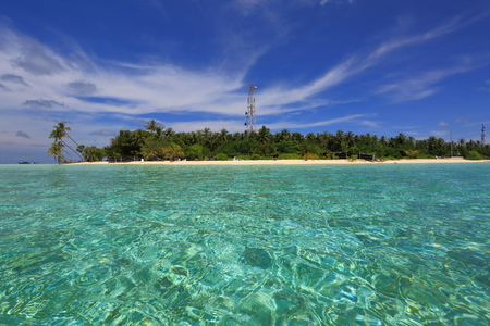 Beautiful view of island in Indian Ocean, Maldives. Turquoise water, white sand beach and green trees on blue sky background.の写真素材