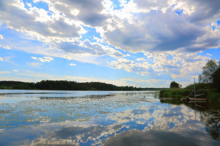 Gorgeous view of the natural landscape on a summer day. Lake and blue sky converging on the horizon. Blue sky and white clouds reflecting on water surface. Beautiful colorful nature background.の写真素材