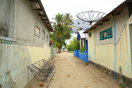 View of a streest on a local island, Maldives, Dhangethi. Traditional outdoor rope chairs. Poor environment and beautiful nature. Green palm trees on background.の写真素材