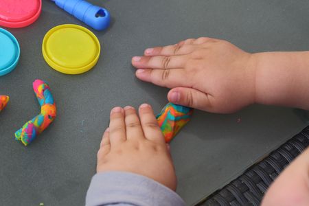 Child's hands playing with colorful plasticine. Happy childhood concept. Young children background.の写真素材