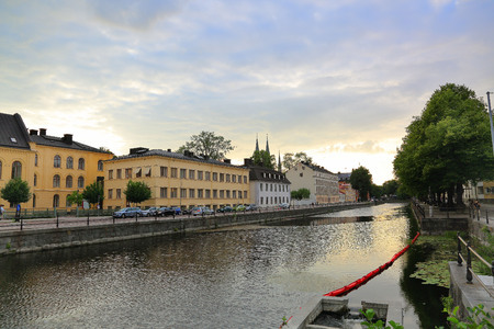 Beautiful landscape view of riverside, Uppsala, Sweden, Europe. Yellow buildings and green trees on blue sky background.の写真素材