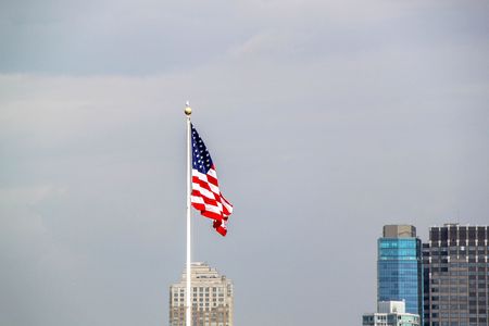 American flag on sky and Manhattan on background.の写真素材
