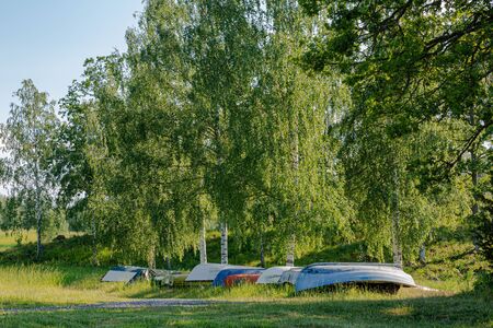 Beautiful lake in the forest near the lake coast line. Inverted boats under blue sky background.の写真素材