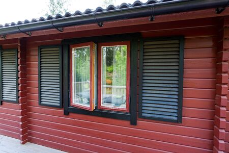 Close up view of facade of typical wooden swedish house. Red walls and contrast black windows. Sweden.Europeの写真素材
