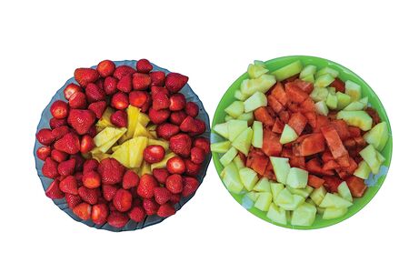 Close up view of two dessert plates isolated. Strawberries with pineapple pieces and watermelon and melon pieces. Beautiful colorful backgrounds. Healthy food concept.の写真素材