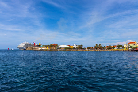 Beautiful view of coast line of Willemstad. Dark blue water surface of Atlantic ocean. Coast line with buildings and big cruise boat merging with blue sky and white clouds. Willemstad. Curasao. 09/09/2019.のeditorial素材