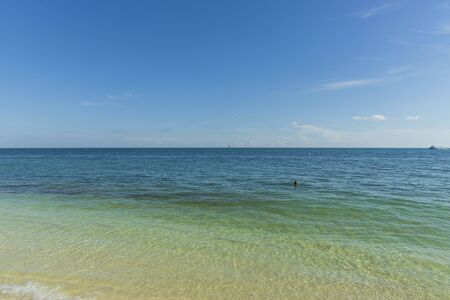 Beautiful view of Atlantic ocean. Blue water surface merging with light blue sky in horizon line. One person is swimming. Key West, Florida. USAの写真素材