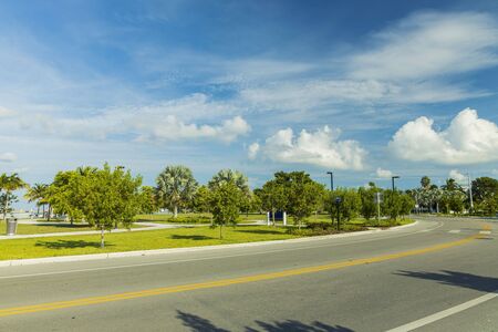 Beautiful view of city landscape. Asphalt road and green tropical trees on blue sky with white clouds background. Key West. Florida USAの写真素材