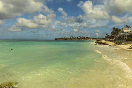 White sand beach and turquoise waves on green palm trees and blue sky background. Aruba. Beautiful backgrounds.の写真素材