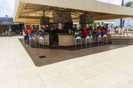 Outdoor bar of Tamarijn resort. Tourists resting on bar chairs. Oranjestad. Aruba. 14/09/2019のeditorial素材