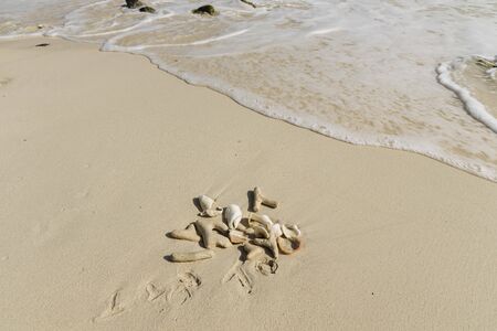Beautiful seascape view. Shells and fancy pebbles on white sand and turquoise rolling waves on background. Atlantic ocean.の写真素材