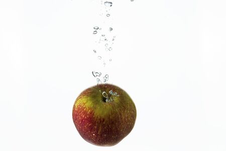 Close up view splashing water and red apple on white background. Beautiful backgrounds.の写真素材