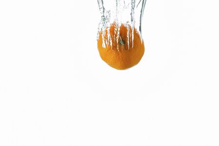 Close up view splashing water and orange mandarin on white background. Beautiful backgrounds.の写真素材