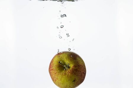 Close up view splashing water and red apple on white background. Beautiful backgrounds.の写真素材
