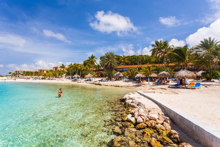 Beautiful view of white sand Curacao beach. Blue sunbeds under sun umbrellas on turquoise water and blue sky with white clouds background. Curacao Island. Beautiful backgrounds.のeditorial素材