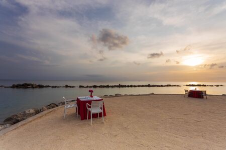 Gorgeous colorful view of sunset on Curacao island. Beautiful view of tables covered with white cloth on coast of Atlantic ocean. Romantic concept. Willemstad.の写真素材