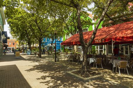 Beautiful view of outdoor cafe on one of Willemstad streets. Beautiful buildings and green trees on background. Eating out concept. Tourism concept. Willemstad. Curacao.の写真素材