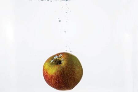 Close up view splashing water and red apple on white background. Beautiful backgrounds.の写真素材