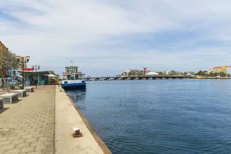 Beautiful view of coast line of Willemstad. Dark blue water surface of Atlantic ocean. Coast line with buildings merging with blue sky and white clouds. Willemstad. Curacao.の写真素材